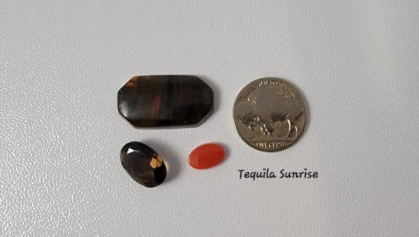One red coral cabochon, one Australian tiger iron cabochon and one topaz faceted stone